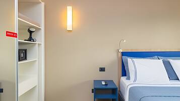 Een hotelkamer met een bed, nachtkastje, plankenwand en een wandlamp.
