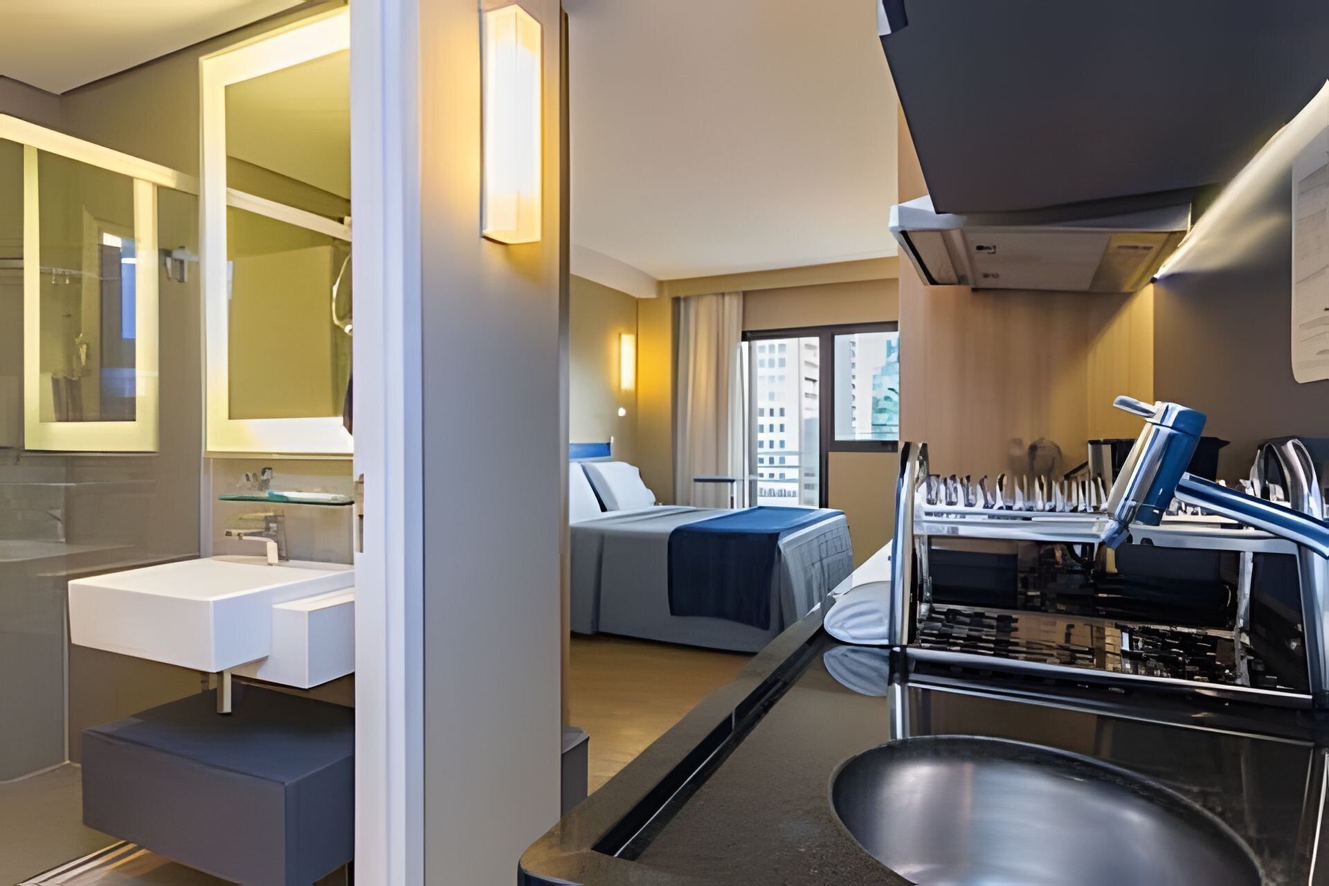 Ein kompaktes Hotelzimmer mit modernem Bad, einem Bett mit Blick und einer Küchenzeile.