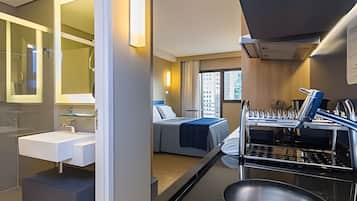 Ein kompaktes Hotelzimmer mit modernem Bad, einem Bett mit Blick und einer Küchenzeile.