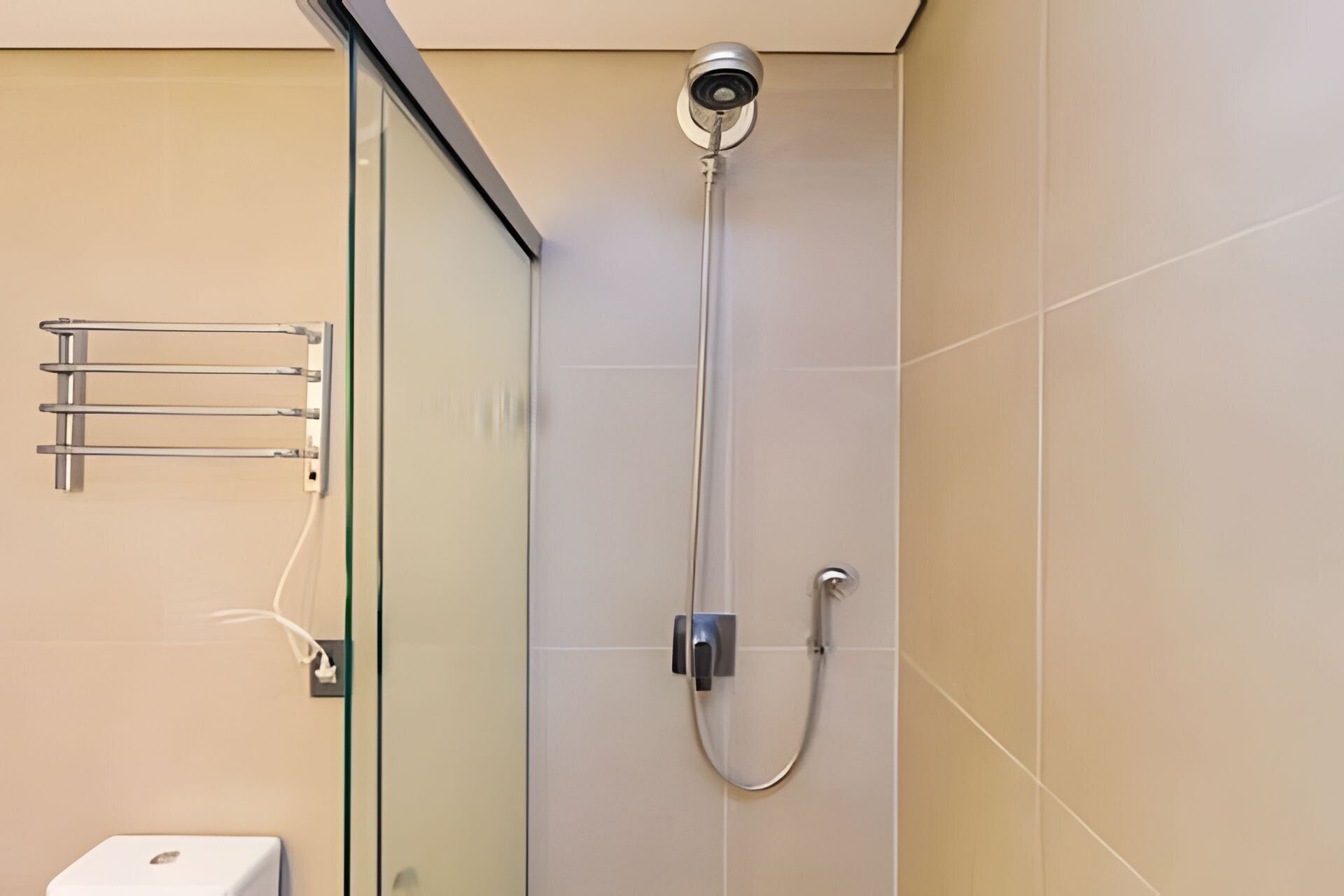 A modern shower with a glass enclosure, a handheld showerhead, and a wall-mounted faucet.