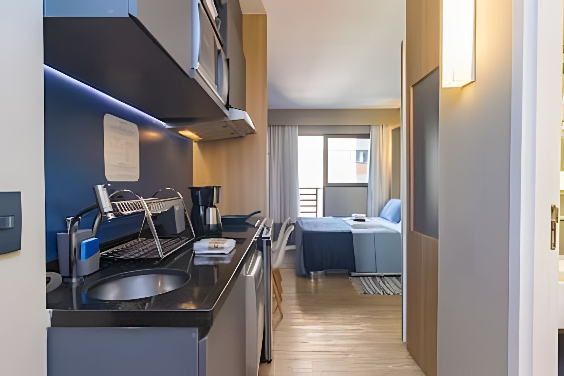 Habitación de hotel compacta con kitchenette, una cama y vistas al exterior.