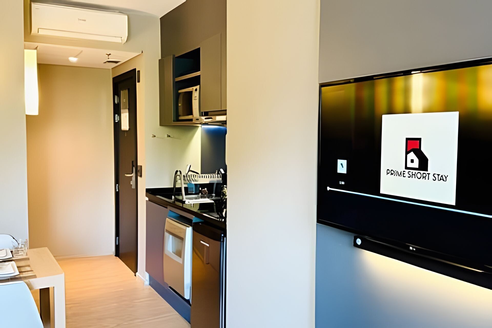 Una cocina moderna con electrodomésticos integrados, una zona de comedor con mesa y sillas, y una pantalla digital montada en la pared.