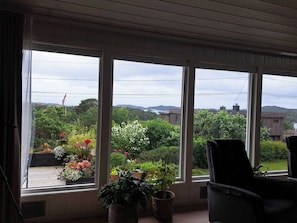A room with large windows, a chair, and potted plants. - Unique villa with good sun conditions and fantastic views (Agder)