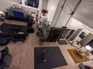 A spacious living area with a black sofa set, a coffee table, and a hanging swing. - Unique villa with good sun conditions and fantastic views (Agder)