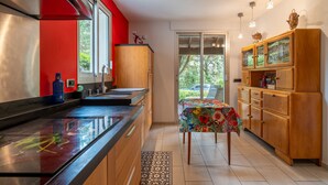Une cuisine moderne dotée d’une hotte en acier inoxydable, de meubles en bois et d’un coin repas avec une table recouverte d’une nappe colorée.