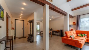 Un vaste espace de vie agrémenté d’un canapé orange vif, d’une table basse en bois et d’une table à manger avec des chaises.
