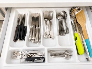 A drawer with neatly organized cutlery including forks, knives, spoons, and a corkscrew. - Elegant 3BR Apartment with Ensuite Baths in Central Naples (Napoli)