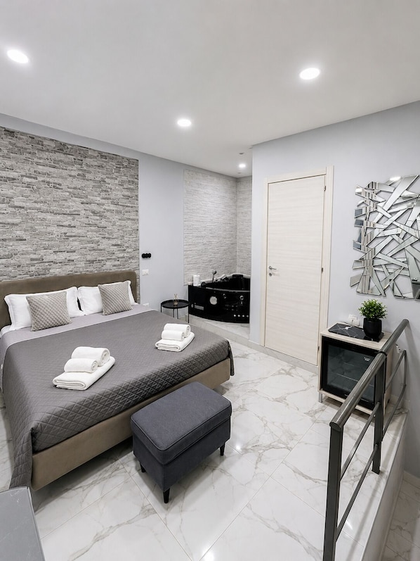 A modern bedroom with a large bed, a small side table, a black cabinet, and a decorative wall piece. - Elegant 3BR Apartment with Ensuite Baths in Central Naples (Napoli)