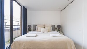 A modern bedroom with a large bed, two bedside tables, and a view of the outside. - Stylish 3-Bed Apartment in South Kensington (Greater London)