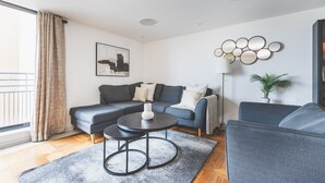 A modern living room with a sectional sofa, a round coffee table, and a floor lamp. - Stylish 3-Bed Apartment in South Kensington (Greater London)