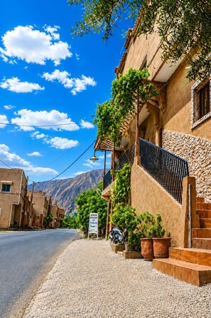 A building with a stone facade, a signboard, and a staircase leading to a terrace.