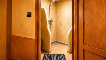 A hotel bathroom with a shower, a towel rack, and a door with a wooden frame.
