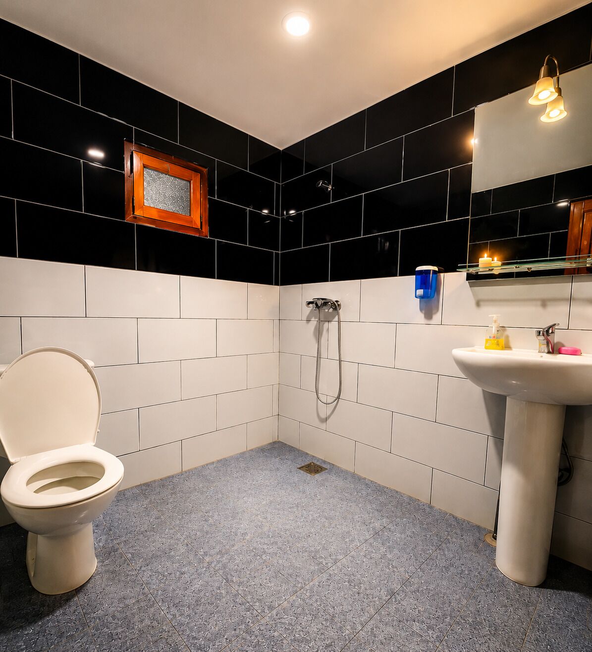 Un baño con inodoro, ducha, lavamanos y espejo.