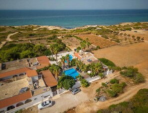 Luftaufnahme eines Küsteneigentums mit Schwimmbad, Strand und Zufahrtsweg.