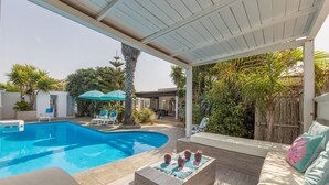 A pool area with a covered patio, lounge chairs, and a seating area with cushions. - Villa Cotriero Crystal (Gallipoli)