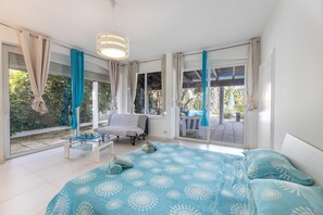 Ein Schlafzimmer mit Bett, Stuhl, Tisch und großen Fenstern.