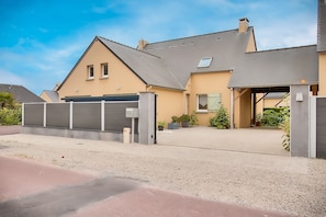 Une maison d’habitation avec une allée, un garage et une entrée fermée par un portail.