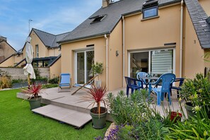 Une propriété résidentielle dotée d’un patio, d’un espace salon extérieur et de plantes en pot.