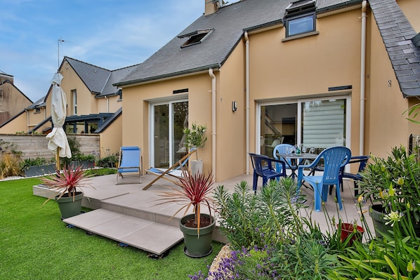 A residential property with a patio, outdoor seating, and potted plants.