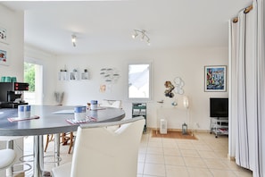 A modern kitchen with a dining area, a TV, and a window.