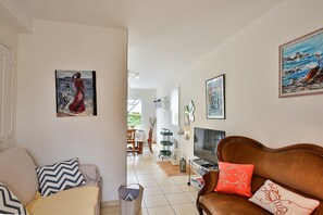 Un salon avec un canapé, un téléviseur et des œuvres d’art accrochées aux murs.