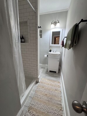 A bathroom with a white sink, a mirror, a towel rack, and a shower area.