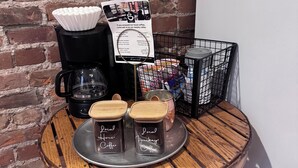 Eine Kaffeestation mit Kaffeemaschine, einem Schild und zwei Behältern, beschriftet mit 'Local House Coffee' und 'Local Lucky Coffee', auf einer Holztischplatte.