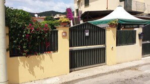 A yellow building with a gated entrance, a satellite dish, and a balcony with a green awning. - Casa Iride - a breath away from the sea
A stone's throw from paradise (Chia)