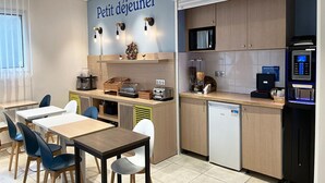 A kitchenette with a microwave, coffee machine, and a small refrigerator. There are tables and chairs for dining. - Comfortable Studio for 2 by the Marne (Nogent-sur-Marne)