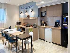A kitchenette with a microwave, coffee machine, and a small refrigerator. There are tables and chairs for dining. - Comfortable Studio for 2 by the Marne (Nogent-sur-Marne)