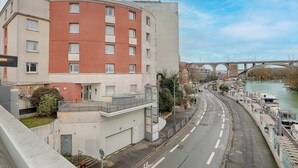 A multi-story building with a red brick facade, a flat roof, and a pedestrian walkway. - Comfortable Studio for 2 by the Marne (Nogent-sur-Marne)