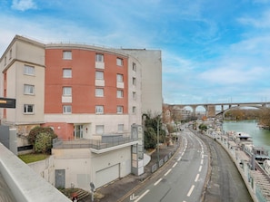 A multi-story building with a red brick facade, a flat roof, and a pedestrian walkway. - Comfortable Studio for 2 by the Marne (Nogent-sur-Marne)