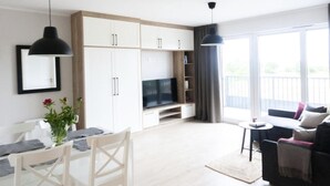 Un soggiorno moderno con zona pranzo, televisione a schermo piatto e balcone con vista.