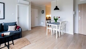 Un soggiorno moderno con un divano, un tavolo da pranzo con sedie e una cucina sullo sfondo.