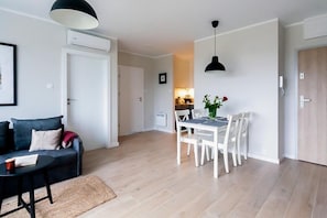 A modern living room with a sofa, a dining table with chairs, and a kitchen in the background. - Cozy Apartment for 4 in West Pomeranian (Dziwnów)