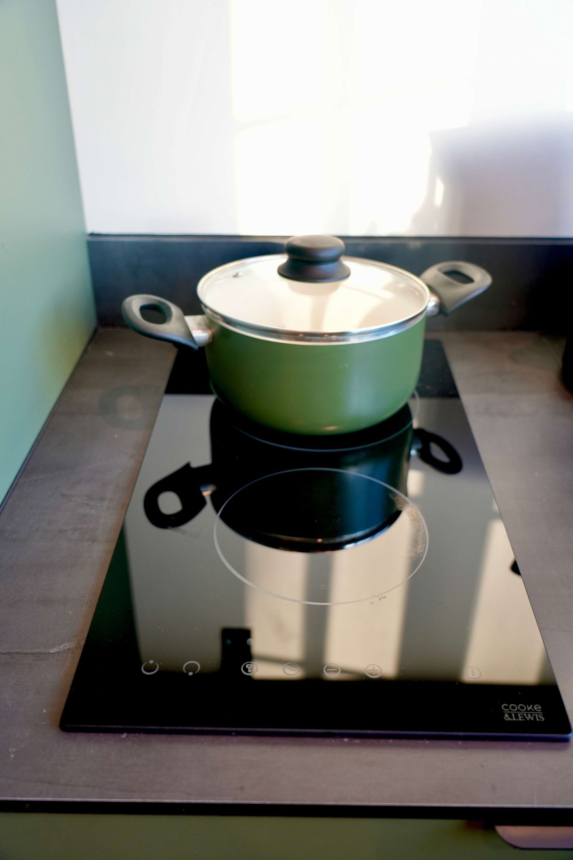 Un faitout vert sur une plaque de cuisson à induction noire.