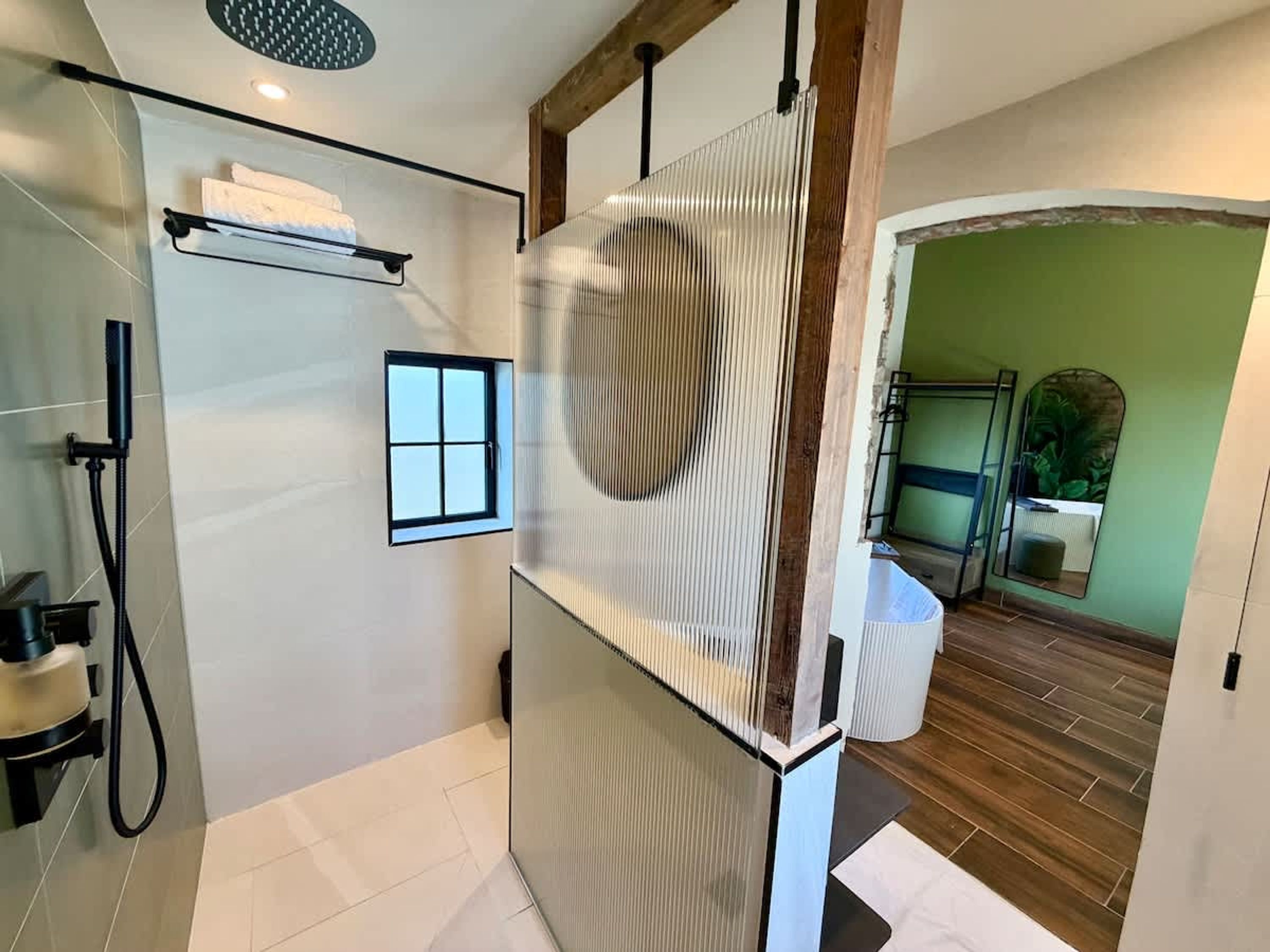 Een moderne badkamer met een douche, een klein raam en een spiegel.