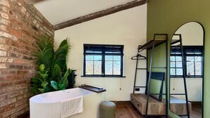 Une salle de bain avec une baignoire, une fenêtre, un miroir et une plante.