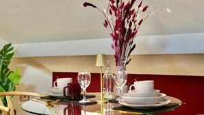 A dining table with white cups, a glass vase with red flowers, and a gold lamp. - Boutique Studio Gold Bath in Jewellery Quarter BHM (Birmingham)