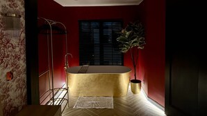 A modern bathroom with a gold bathtub, a shower, and a potted plant. - Boutique Studio Gold Bath in Jewellery Quarter BHM (Birmingham)