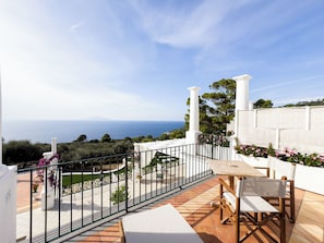 A terrace with a view of the sea, white columns, and a table with chairs. - Amira Resort (Anacapri)