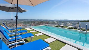 A rooftop pool with blue lounge chairs and a view of the city. - Apartment 'Colina Do Sol 1' with Mountain View, Wi-Fi and Air Conditioning (Vau)