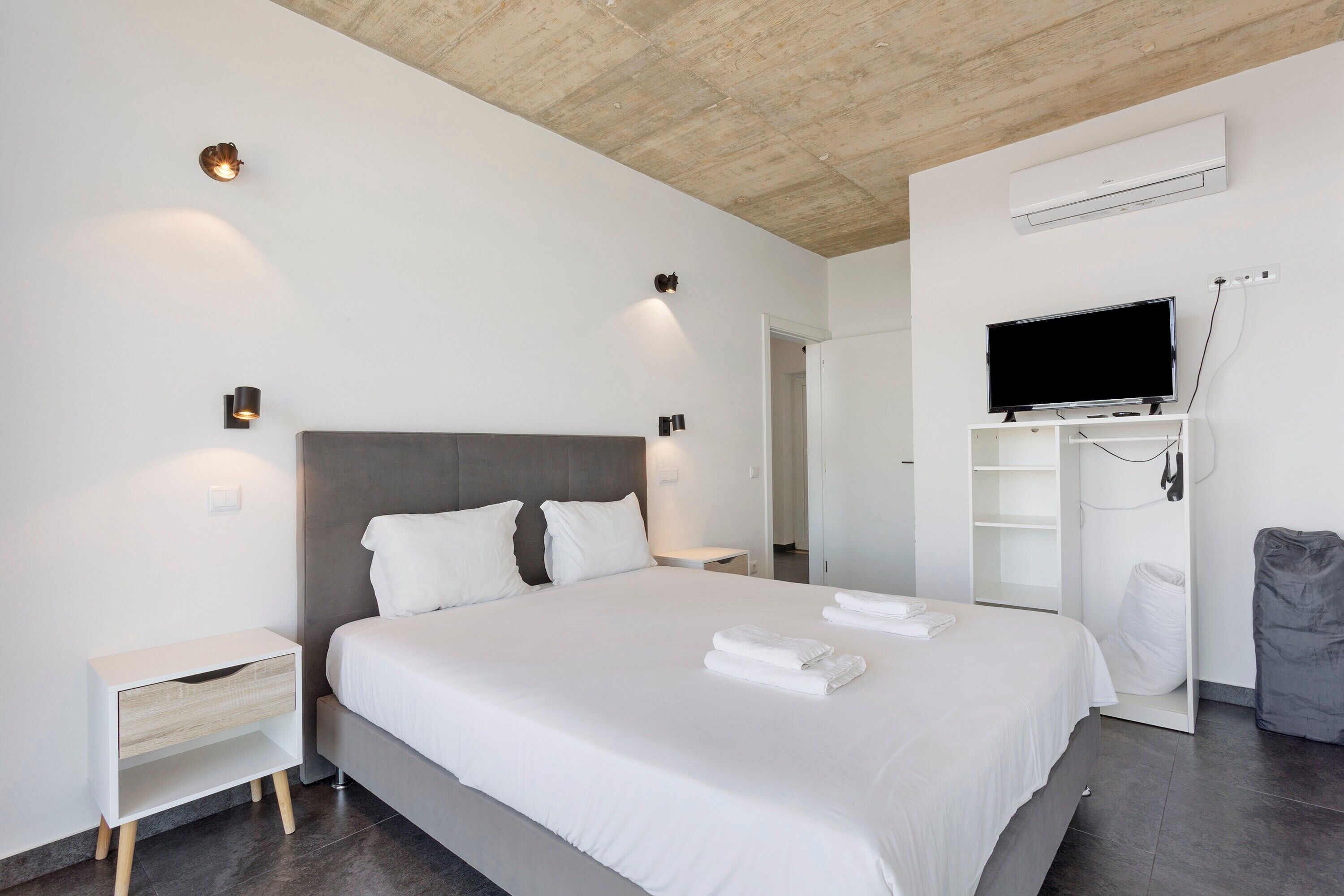 Una habitación de hotel moderna con una cama grande, mesitas de noche, un televisor y un armario.