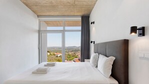 A hotel room with a large bed, a view through a window, and a modern light fixture. - Apartment 'Colina Do Sol 1' with Mountain View, Wi-Fi and Air Conditioning (Vau)