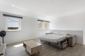 Un dormitorio con cama, escritorio y ventilador de pie.