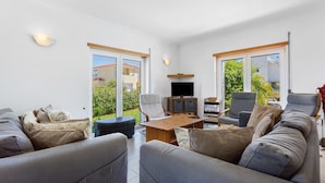 A spacious living room with a sofa set, a wooden coffee table, and a flat-screen TV.