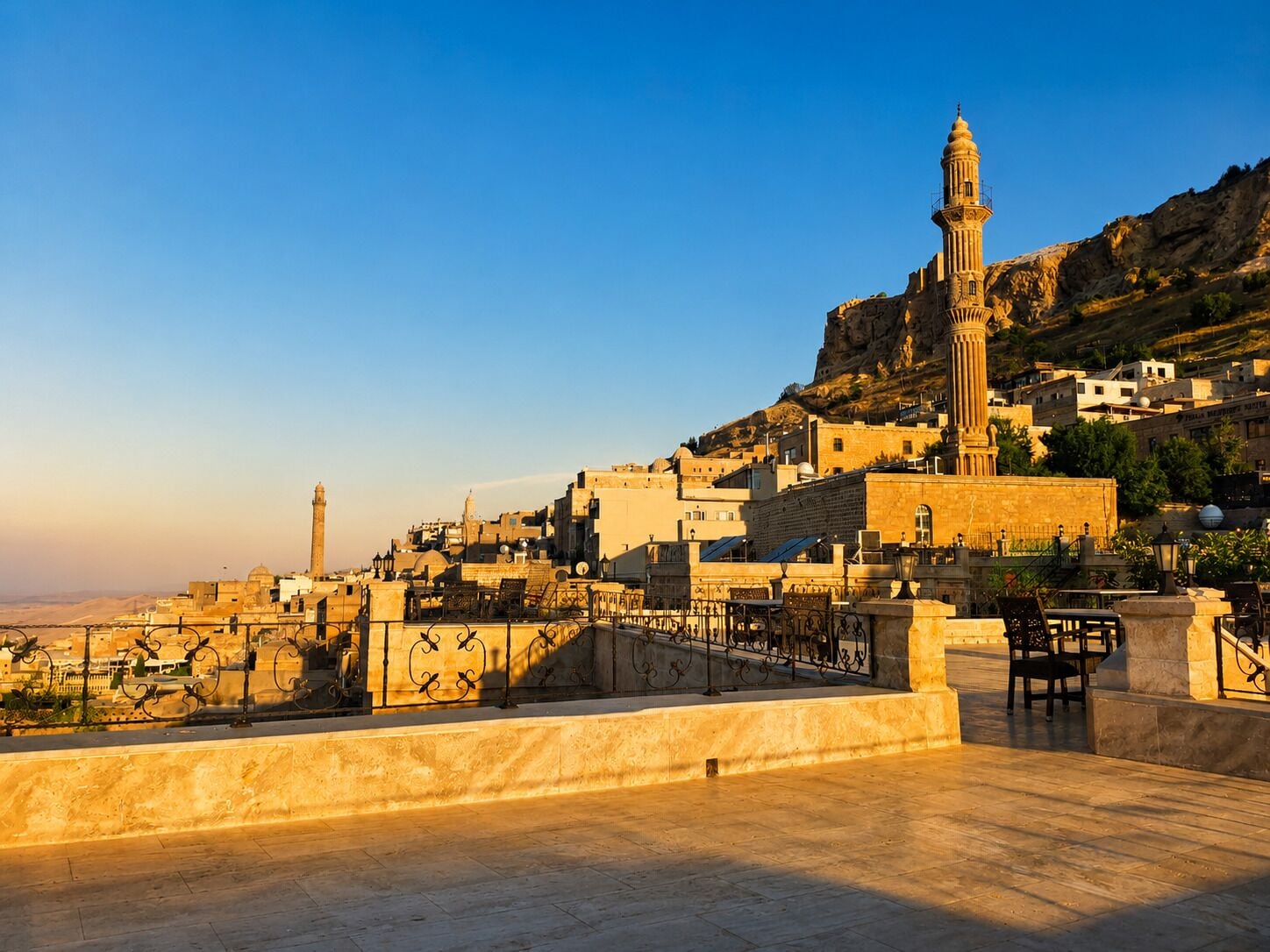 Une terrasse sur le toit offrant une vue sur une ville historique, notamment sur un minaret imposant et une mosquée.
