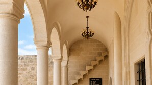 A corridor with columns, a chandelier, and a staircase leading to a room labeled 'GIRLARD / ROOMS'.