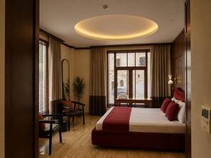 Una habitación de hotel con una cama grande, un escritorio, una silla, una planta en maceta y una ventana con cortinas.