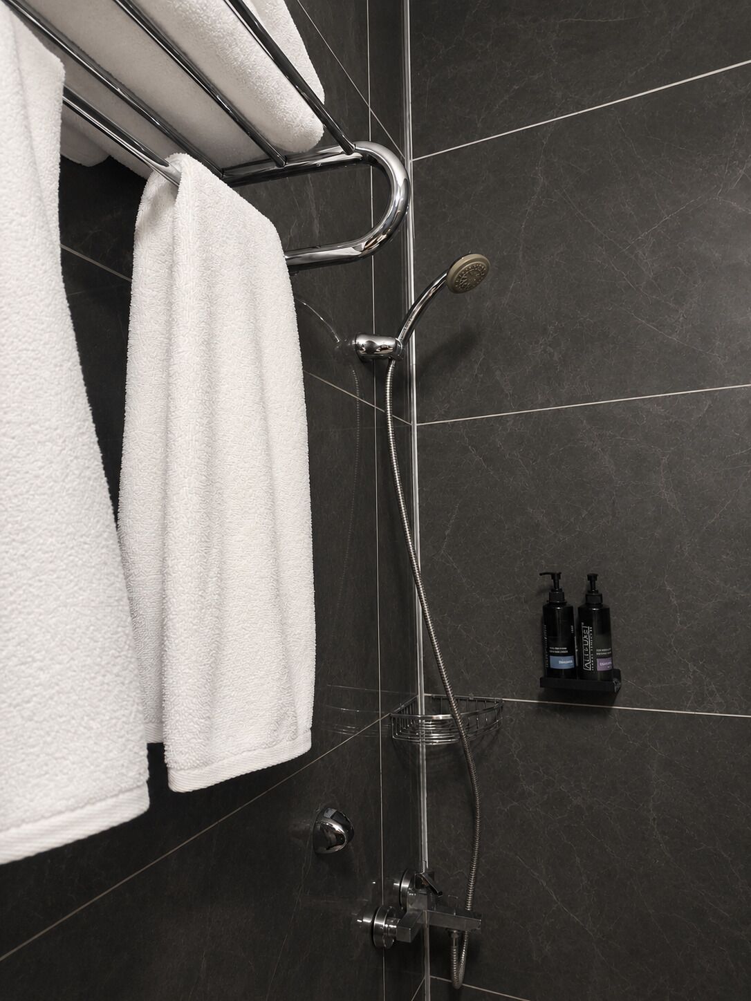 Un baño con ducha, perchero y estante con artículos de aseo.